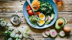 Raw food meal plan ingredients with colorful vegetables fruit nuts seeds avocado herbs and salad bowls
